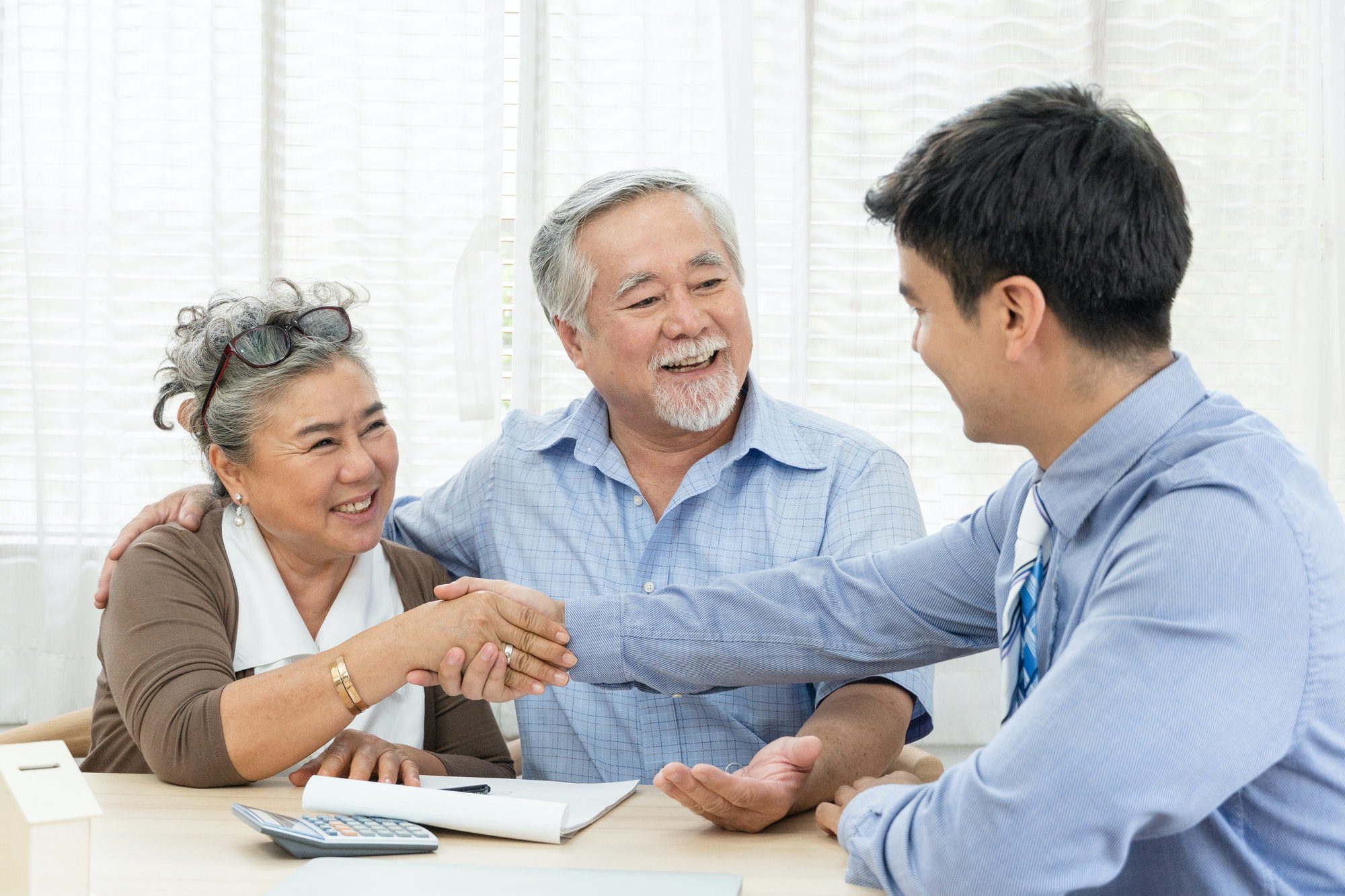 Happy senior couple handshaking with agent from a Medicare Supplement Insurnace Company