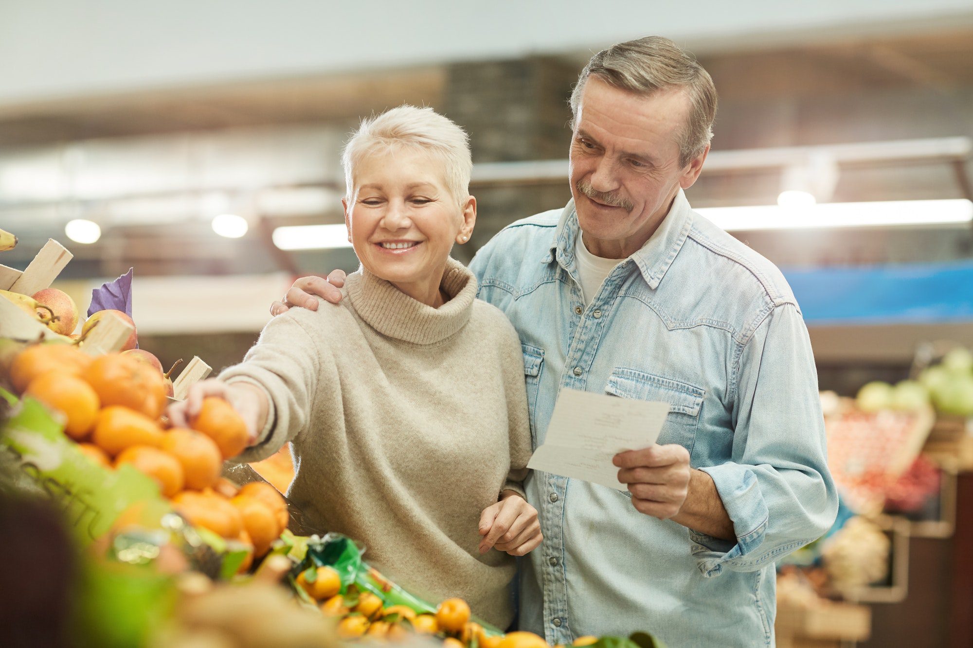Senior couple choosing Fresh Fruits at a Market deciding on how to choose a Medicare Plan.