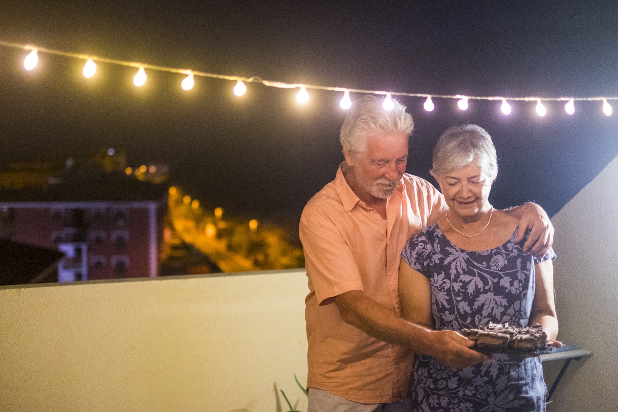 Happy senior adult couple with a chocolate cake as they discuss their social security and medicare premium increases coming in 2022.