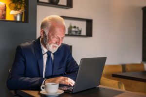 Senior businessman looking over plan F medicare on his laptop