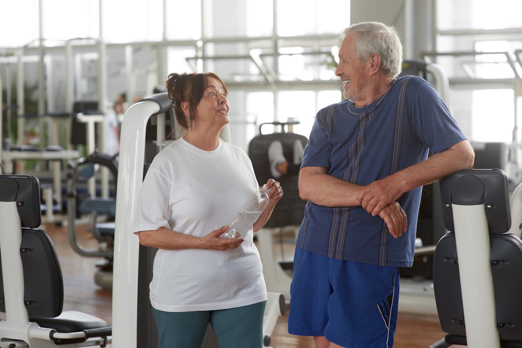 Happy senior couple at gym discussing their health matching account.