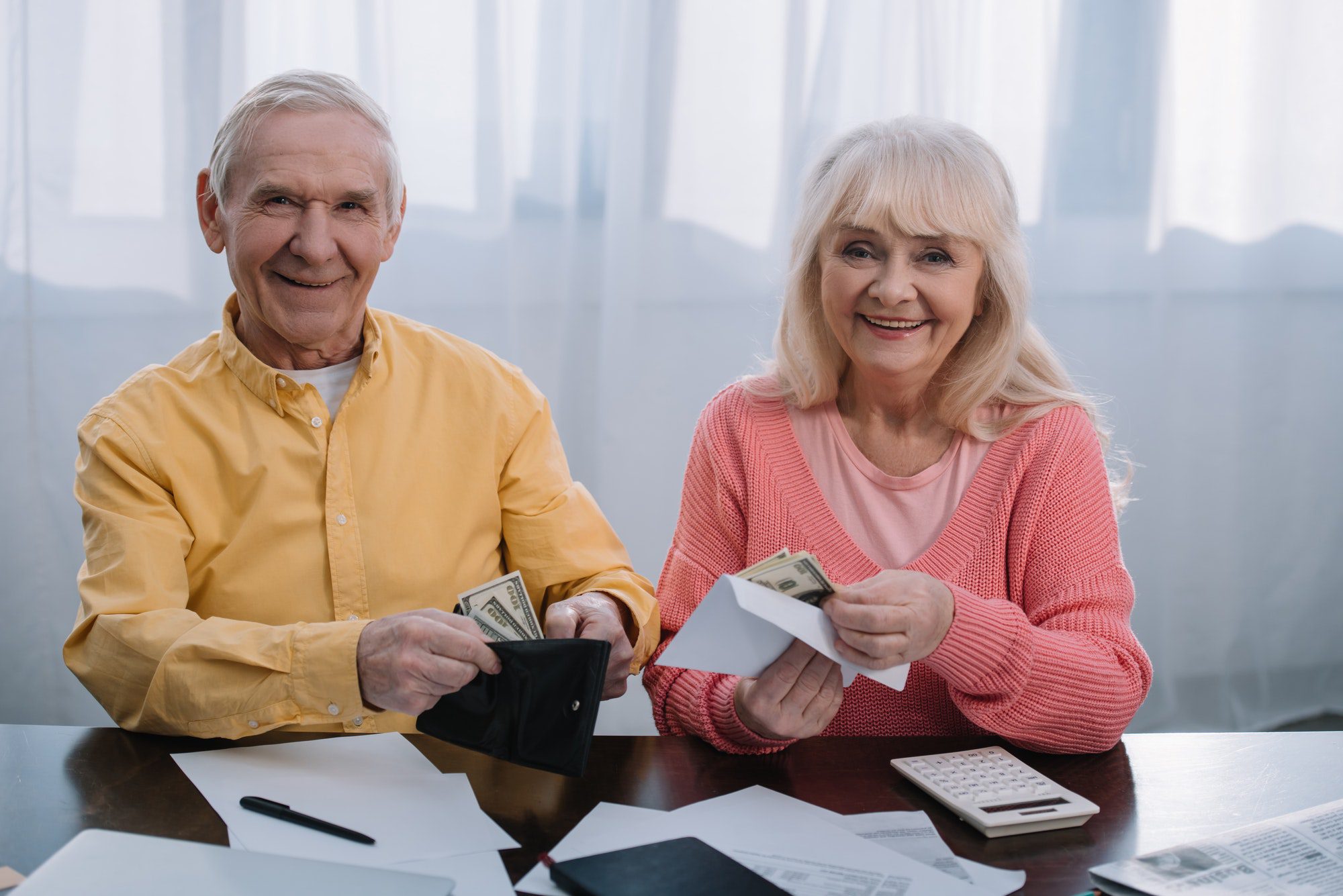 Senior couple holding money to represent medicare deductibles and out of pocket costs.