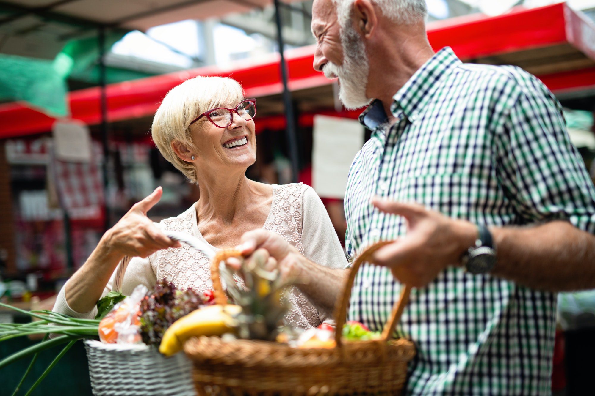 Senior shopping couple with basket on the market. Cost-sharing Medigap Plans K and L